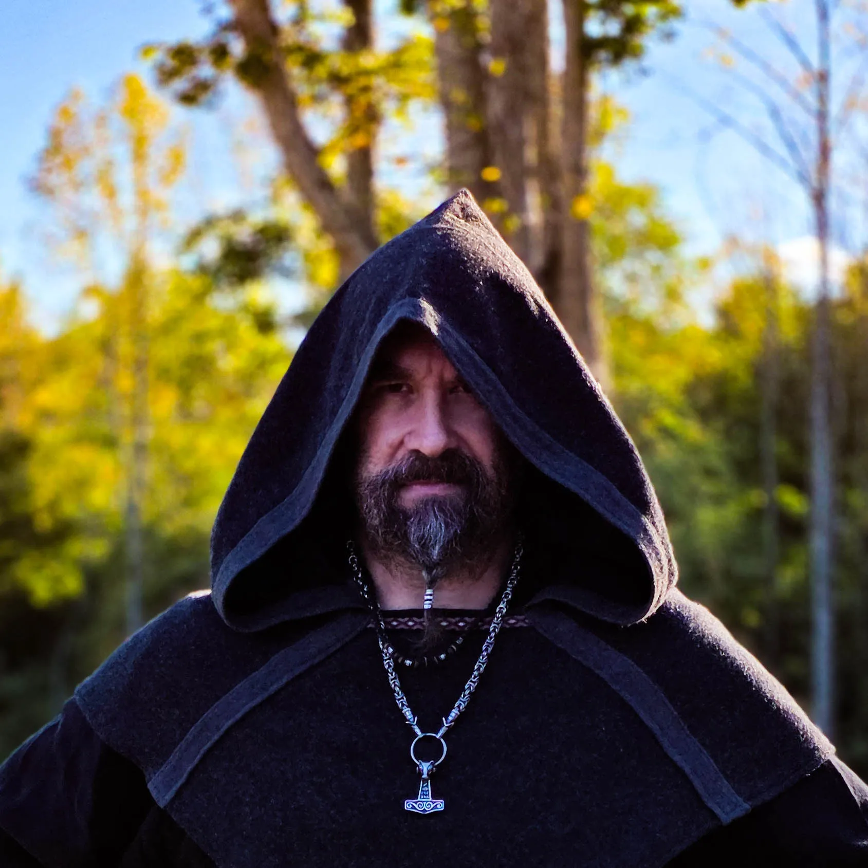 Smedis in a dark wool hood and Thor's hammer pendant